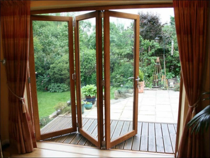An open door leading to a wooden patio, showcasing the fold n slide doors system by Smart Window Solution Industry in Lucknow.